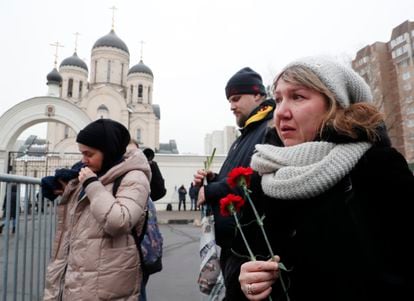 Una mujer sostiene claveles rojos en la mano, en el exterior de la iglesia moscovita, este viernes.